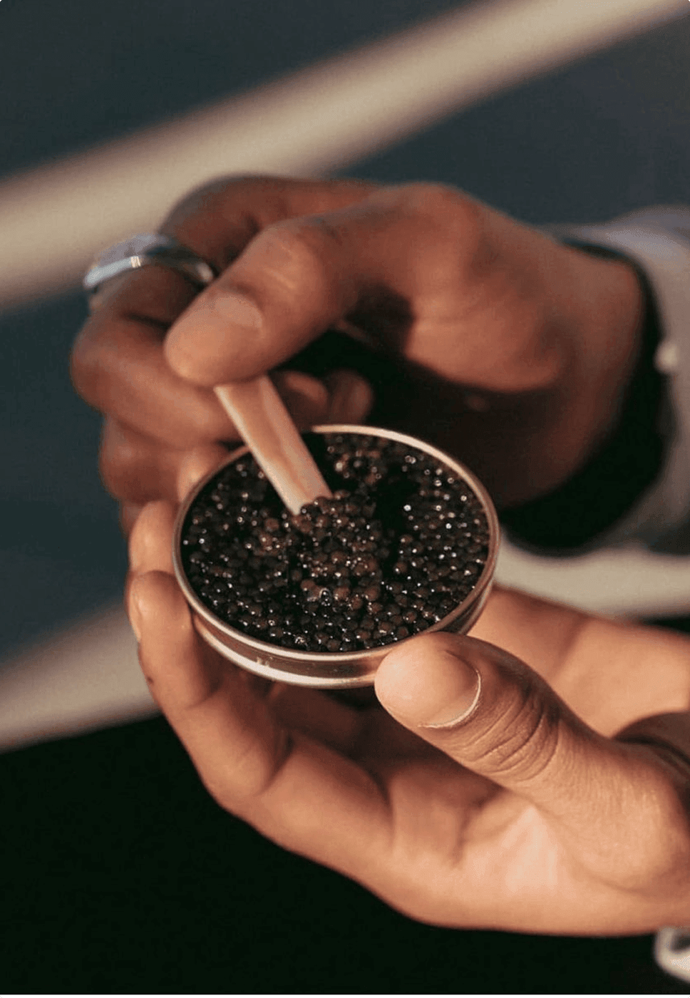 A caviar expert examining pearls in an open tin